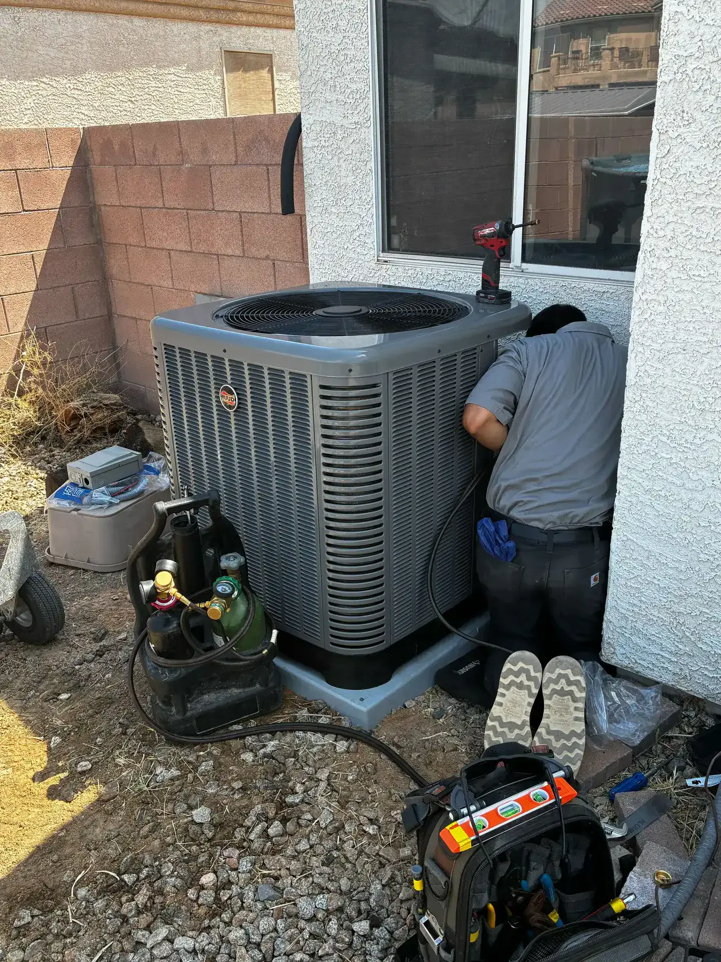 A Hawthorne technician servicing an outdoor heat pump unit
